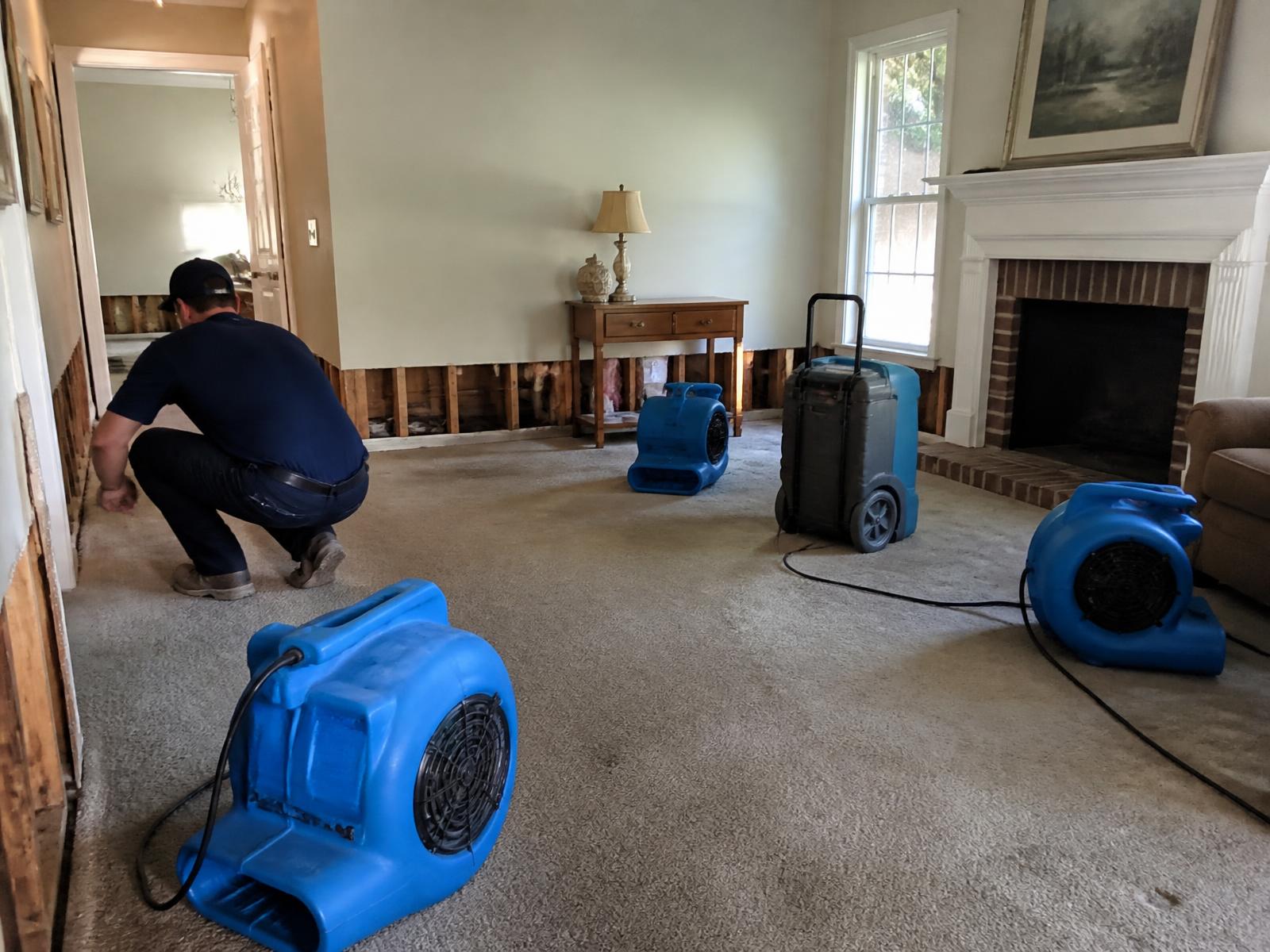 Gator Done technician performing water damage mitigation with air movers and a dehumidifier inside a Lake Charles, Louisiana home